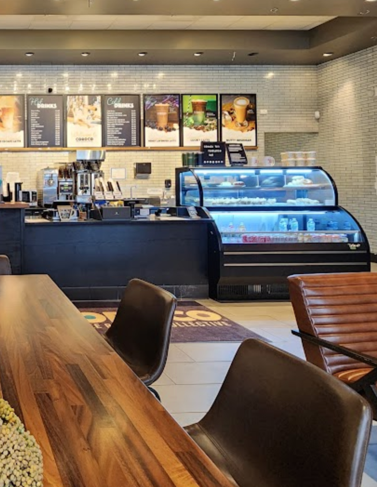 Interior view of Coroco Coffee in St. Charles featuring the full service counter, espresso equipment, menu boards, pastry case, and modern seating.